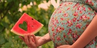 парче лубеница во рака на бремена жена